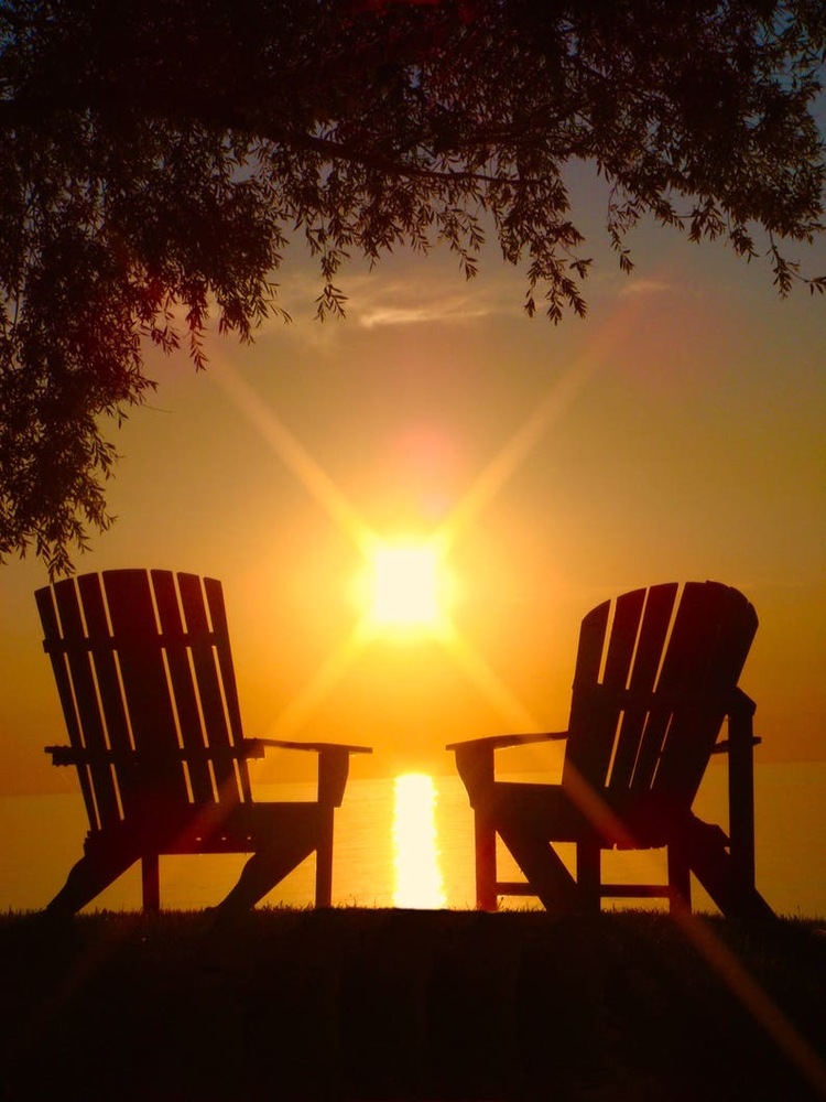 2 chairs with the sun setting in the background